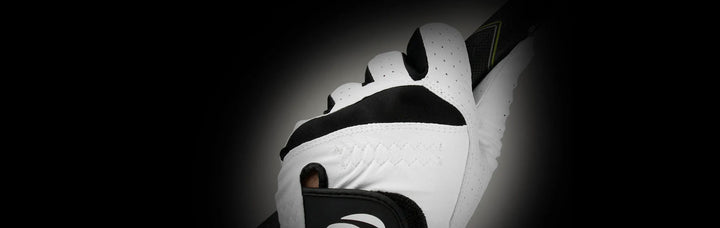 back view of a White/Black Orlimar Tour Cabretta Leather Golf Glove on a person's left hand holding a golf club