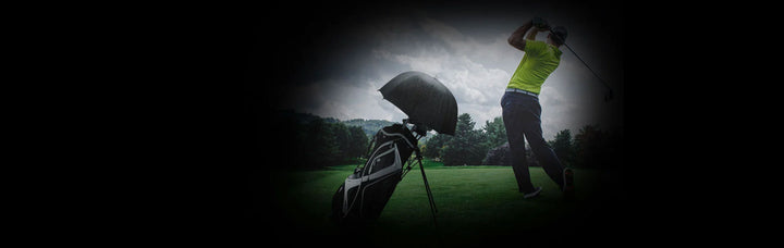 person swinging a golf club on a tee box with an opened Orlimar Dri-Clubz Golf Bag Umbrella inside the bag to keep the golf clubs dry from the rain