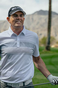 smiling man wearing a black Orlimar golf cap and holding a golf club close to his waist