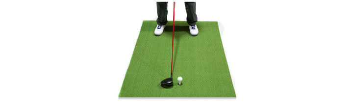 front angled view of a person getting ready to hit a driver with a red graphite shaft off an Orlimar Residential Golf Mat with white golf ball on the rubber tee