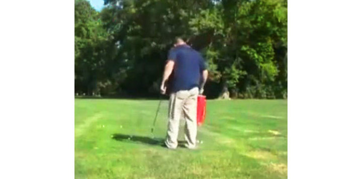 a person picking up golf balls in their backyard with a red Orlimar Golf Shag Bag