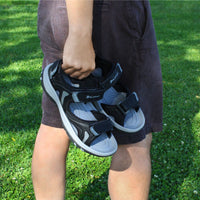 man with shorts carrying pair of men's Orlimar Golf Sandals with Replaceable Spikes