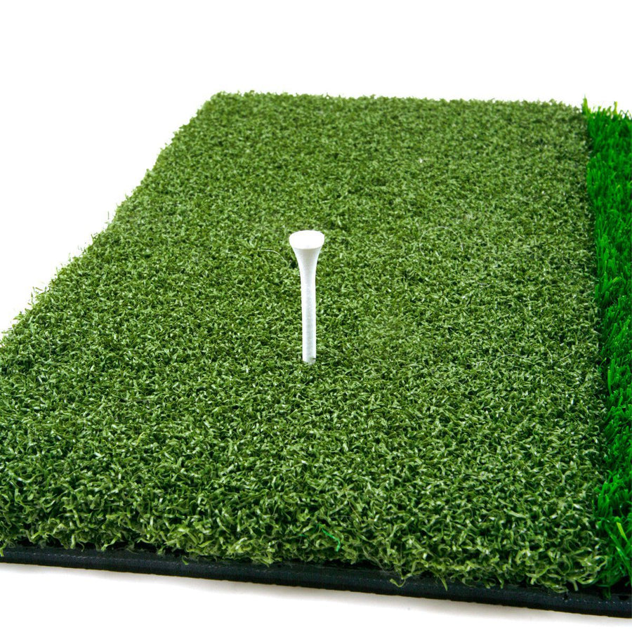 white golf tee stuck in the tee box grass on an Orlimar Triple Surface Golf Hitting Mat